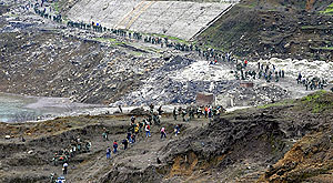 Survivors of the earthquake from Wenchuan City, close to the epicentre, make their way along a collapsed mountain road next to Zipingpu reservoir